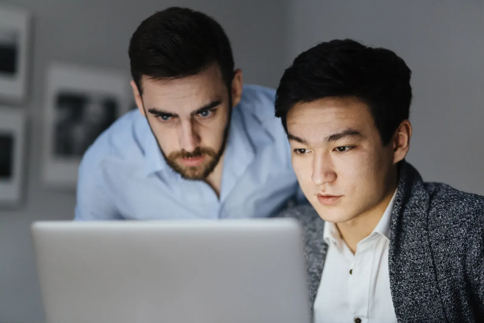 Two men studying information on a laptop screen together