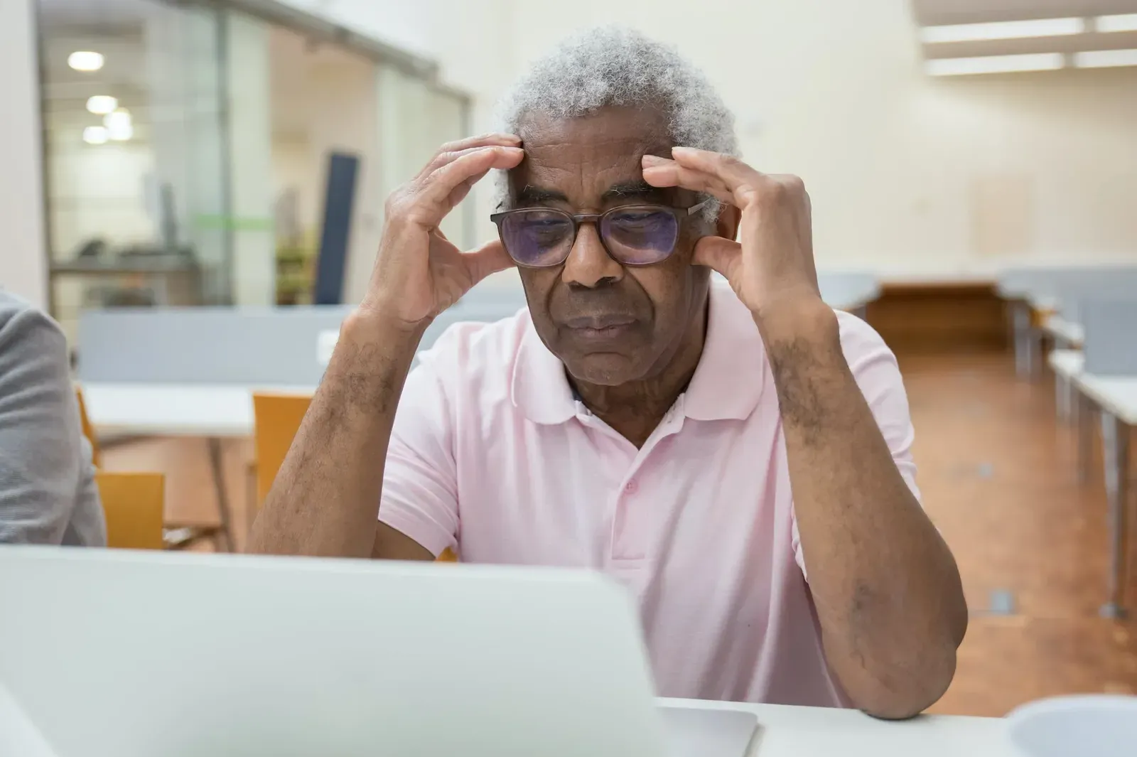 Stressed senior man holding his head in front of a laptop, worried about a data breach