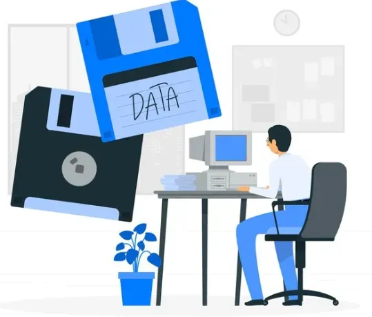 Person at a retro computer desk beside large floppy disks labeled DATA