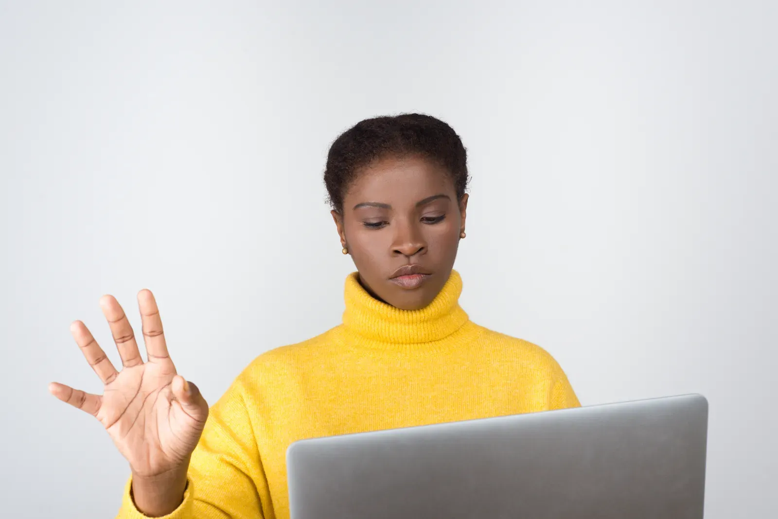 Woman at a laptop raising her hand in a stop gesture to refuse data sharing